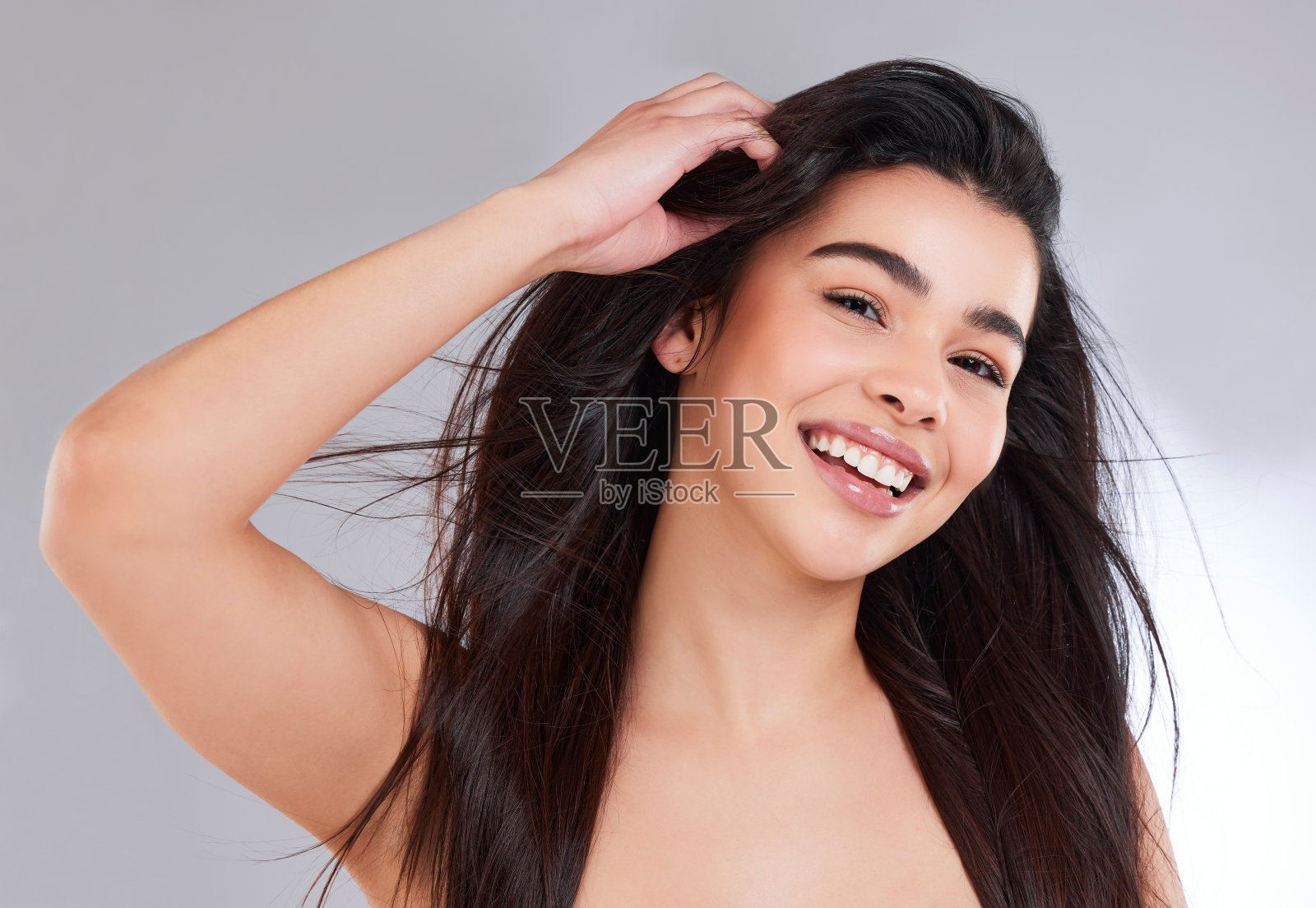 一个迷人的年轻女子在灰色背景下摆姿势的工作室肖像照片摄影图片