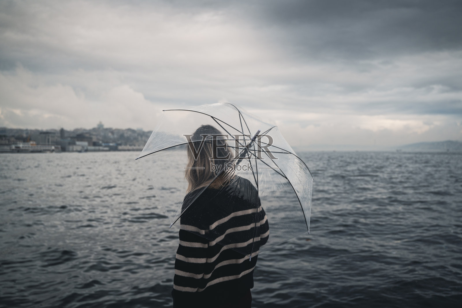 女人撑着透明的伞在水前照片摄影图片