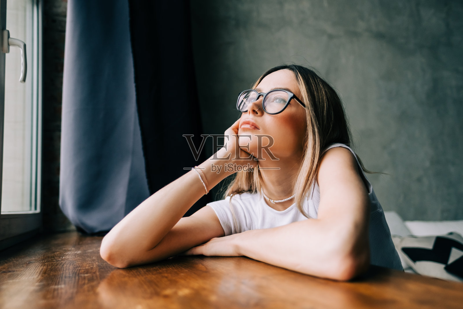 年轻无聊的千禧一代女人独自在家看着窗户。疲惫或情感枯竭的概念照片摄影图片