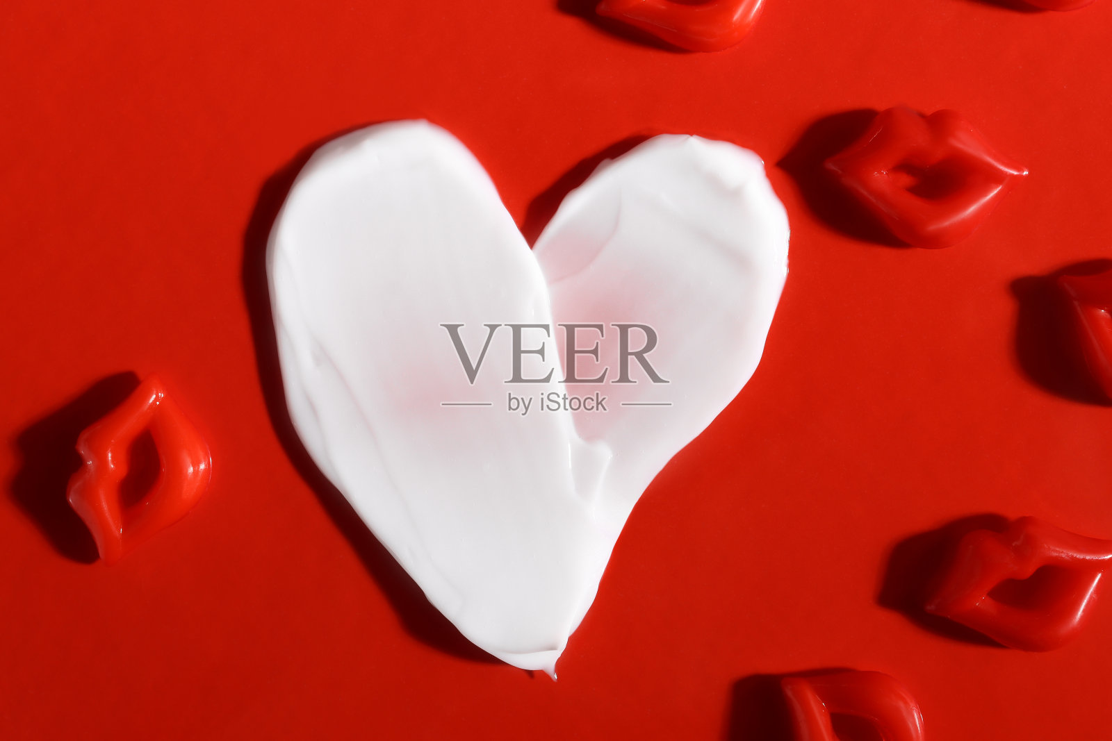 红底心形护肤霜，唇形五彩纸屑。美丽的概念。照片摄影图片