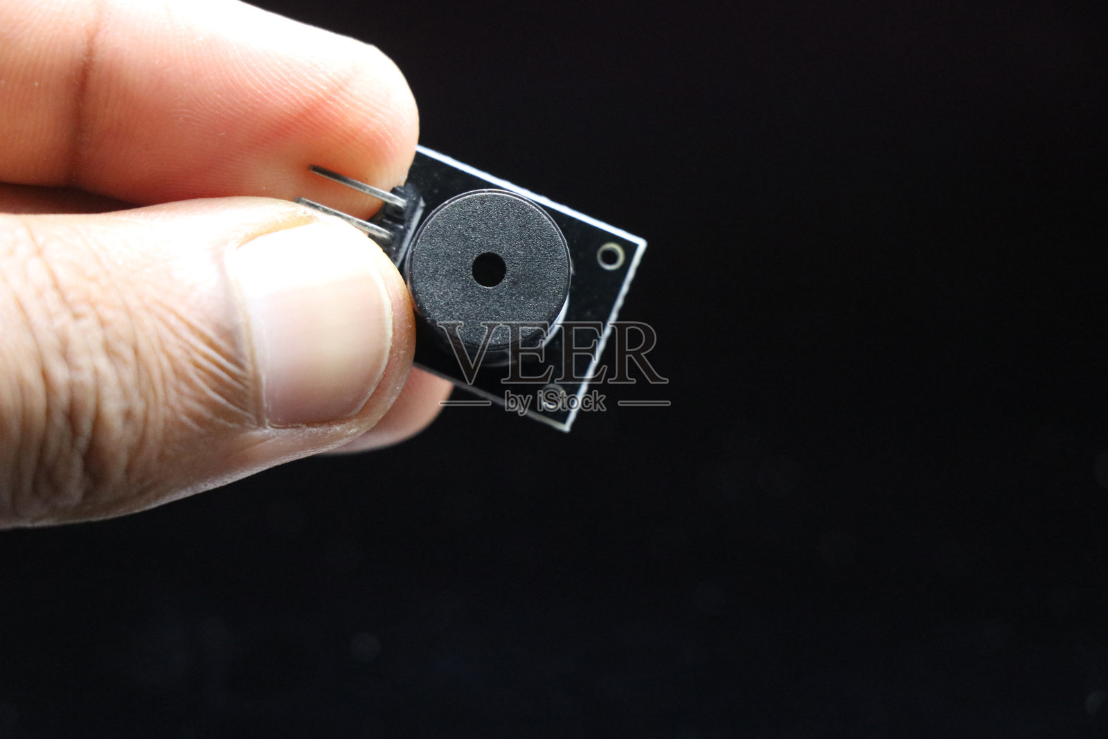 无源蜂鸣器模块用于微控制器等电子项目，手持隔离在黑色背景上照片摄影图片