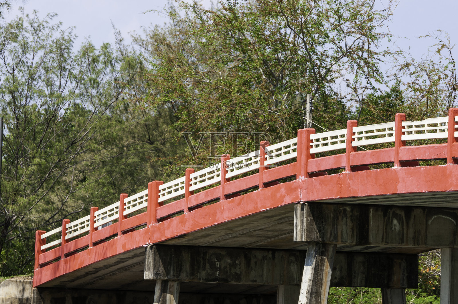 红色水泥车桥，绿树成荫。照片摄影图片