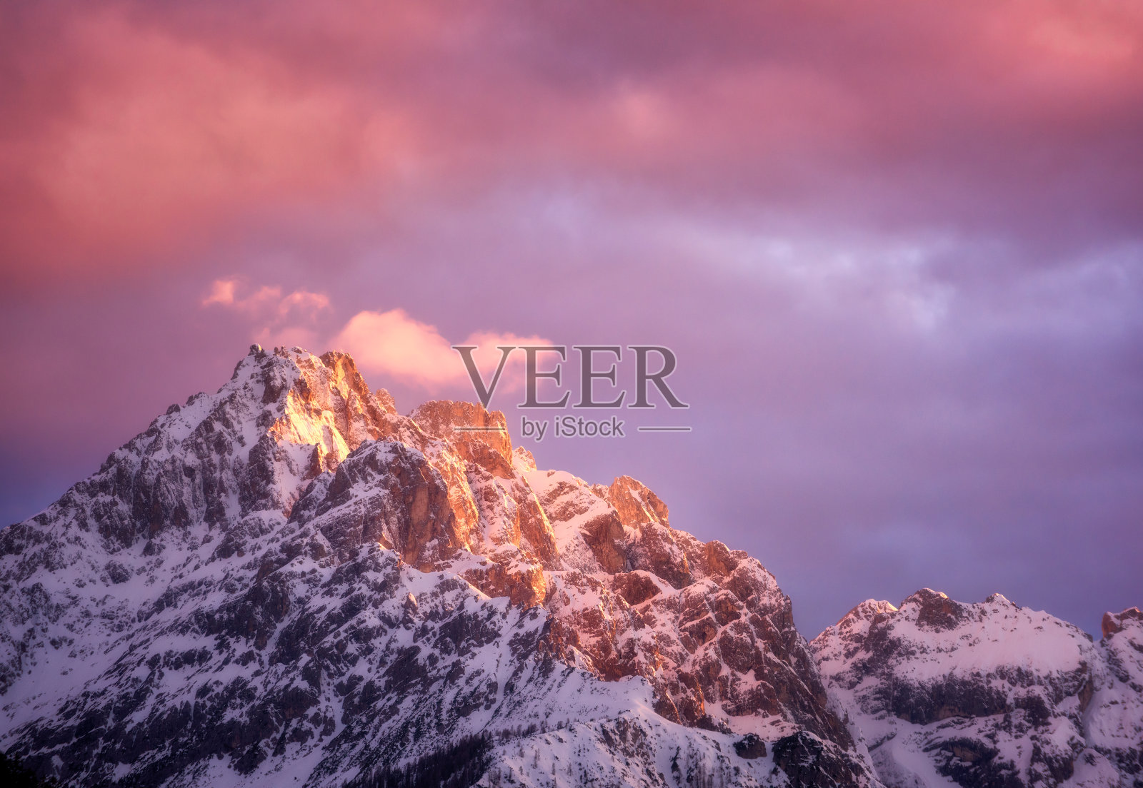 美丽的山峰在雪和紫色的天空和粉红色的云在冬天的日落。高山白石，阴天紫天，景色绚丽多彩。阿尔卑斯山脉。自然背景照片摄影图片