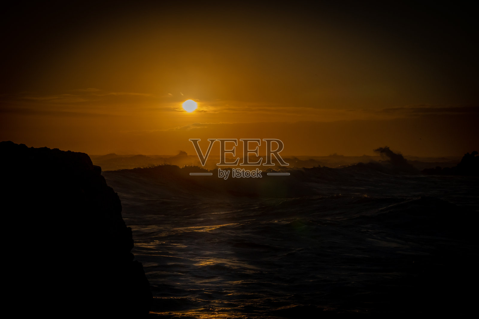 金色的辉光在地平线上，穿过黑暗的背景穿过大海照片摄影图片