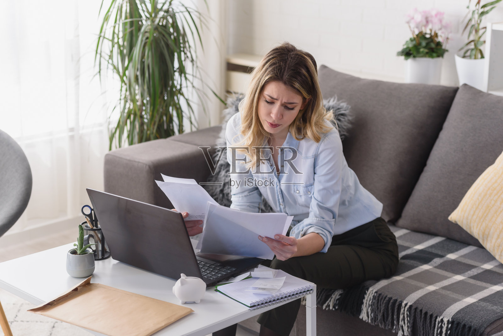 年轻漂亮的女人在家里用电脑工作，计算每月的开销，做家庭预算照片摄影图片