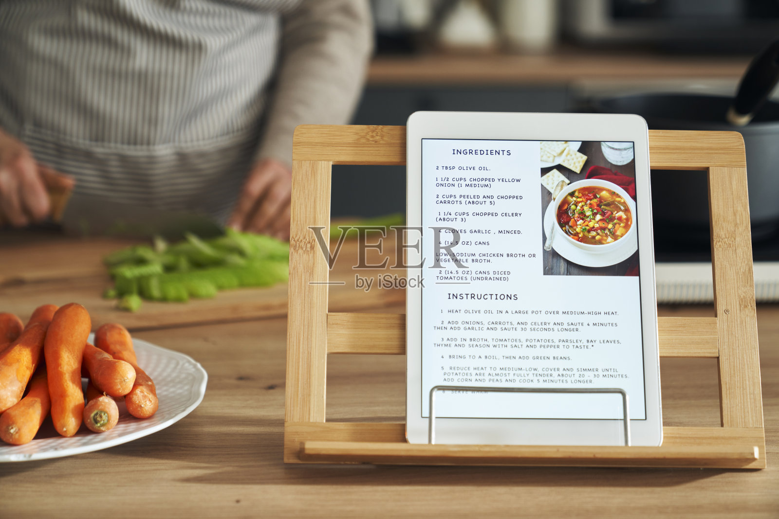 数字平板的细节，汤的配方和背景中的女人照片摄影图片