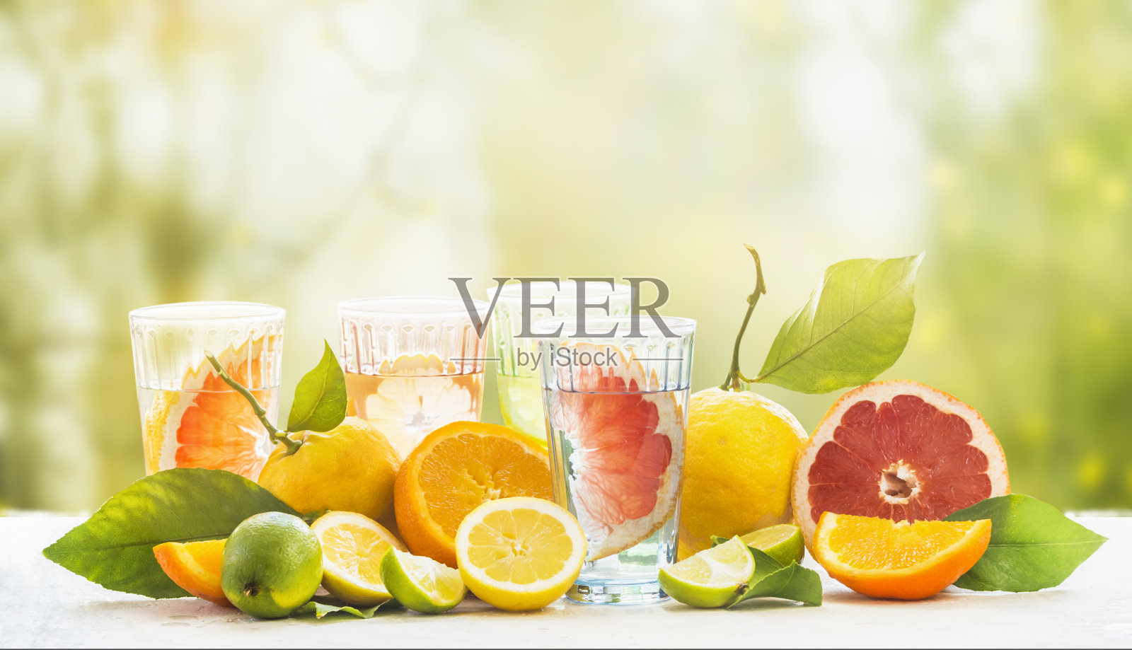 各种健康的夏季柠檬水杯，含有多种有机柑橘类水果。户外。照片摄影图片