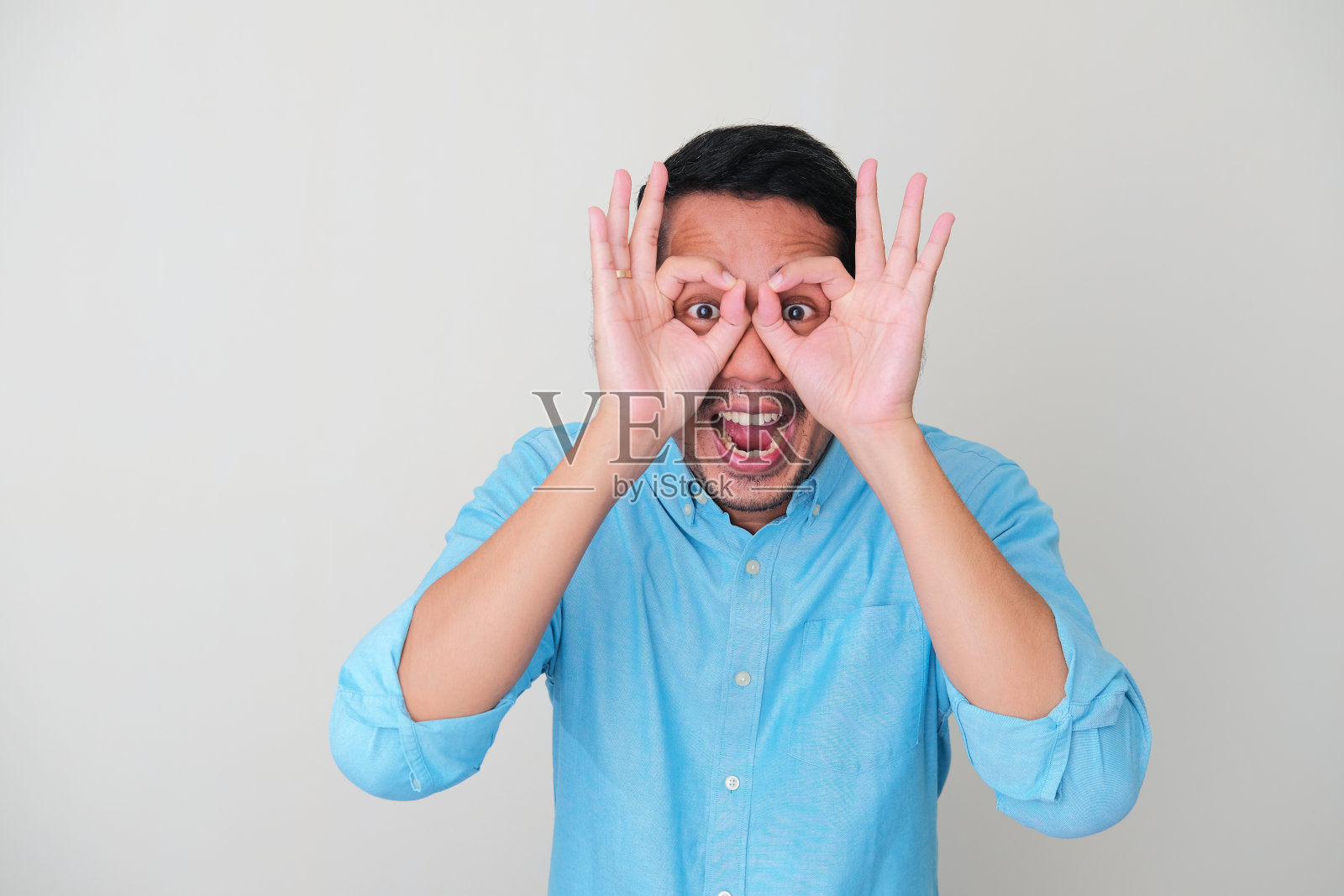 有趣的亚洲人从他自己的手偷看和显示惊讶的表情照片摄影图片