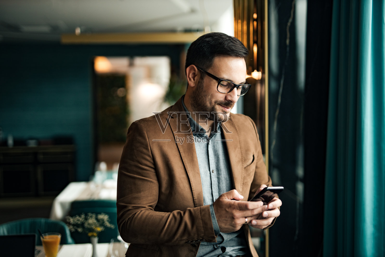 一个微笑的优雅的男人的肖像使用智能手机，短信，特写，复制空间。照片摄影图片
