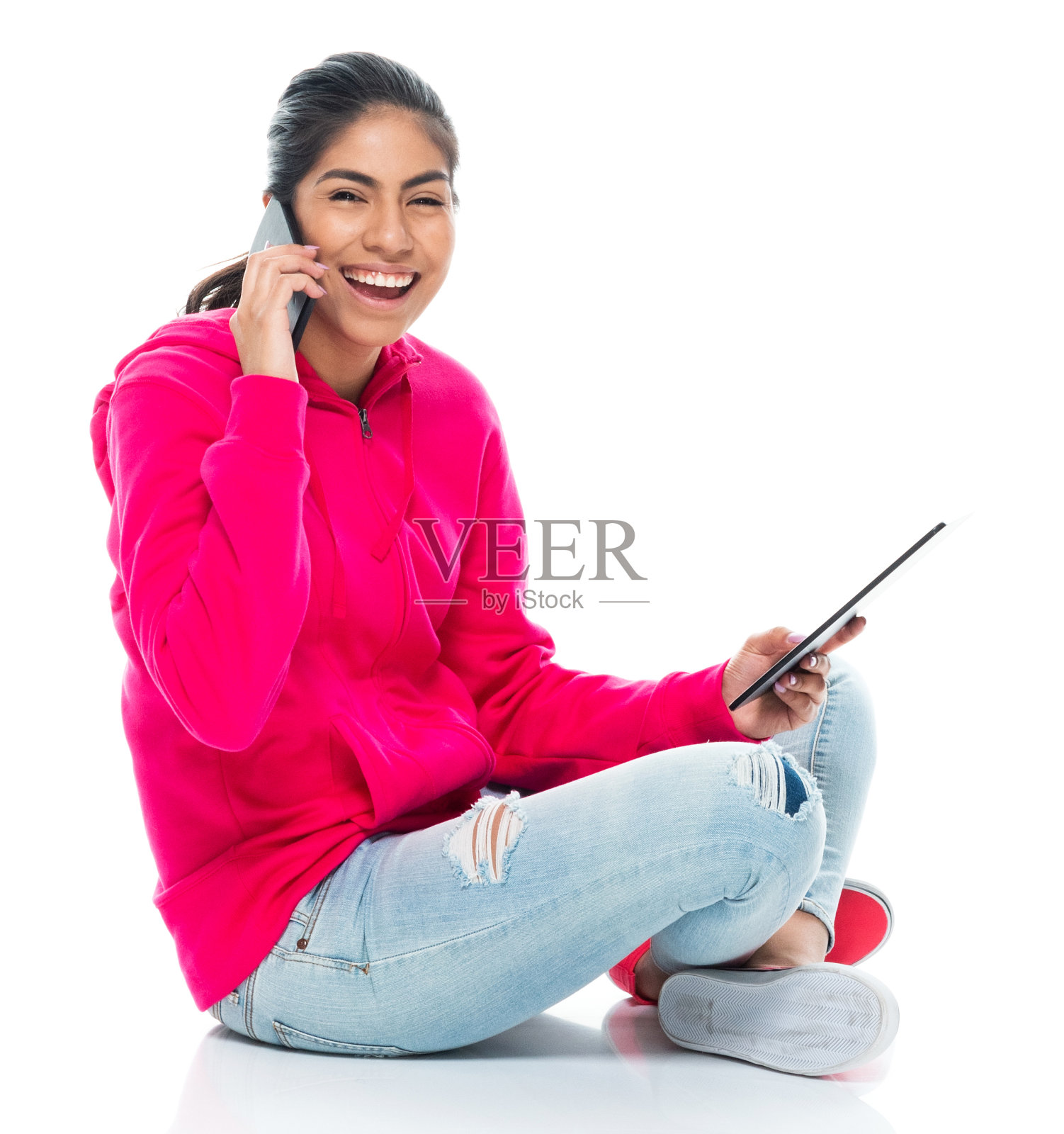 z一代年轻女性坐在白色背景前，穿着帆布鞋，使用数码平板电脑照片摄影图片