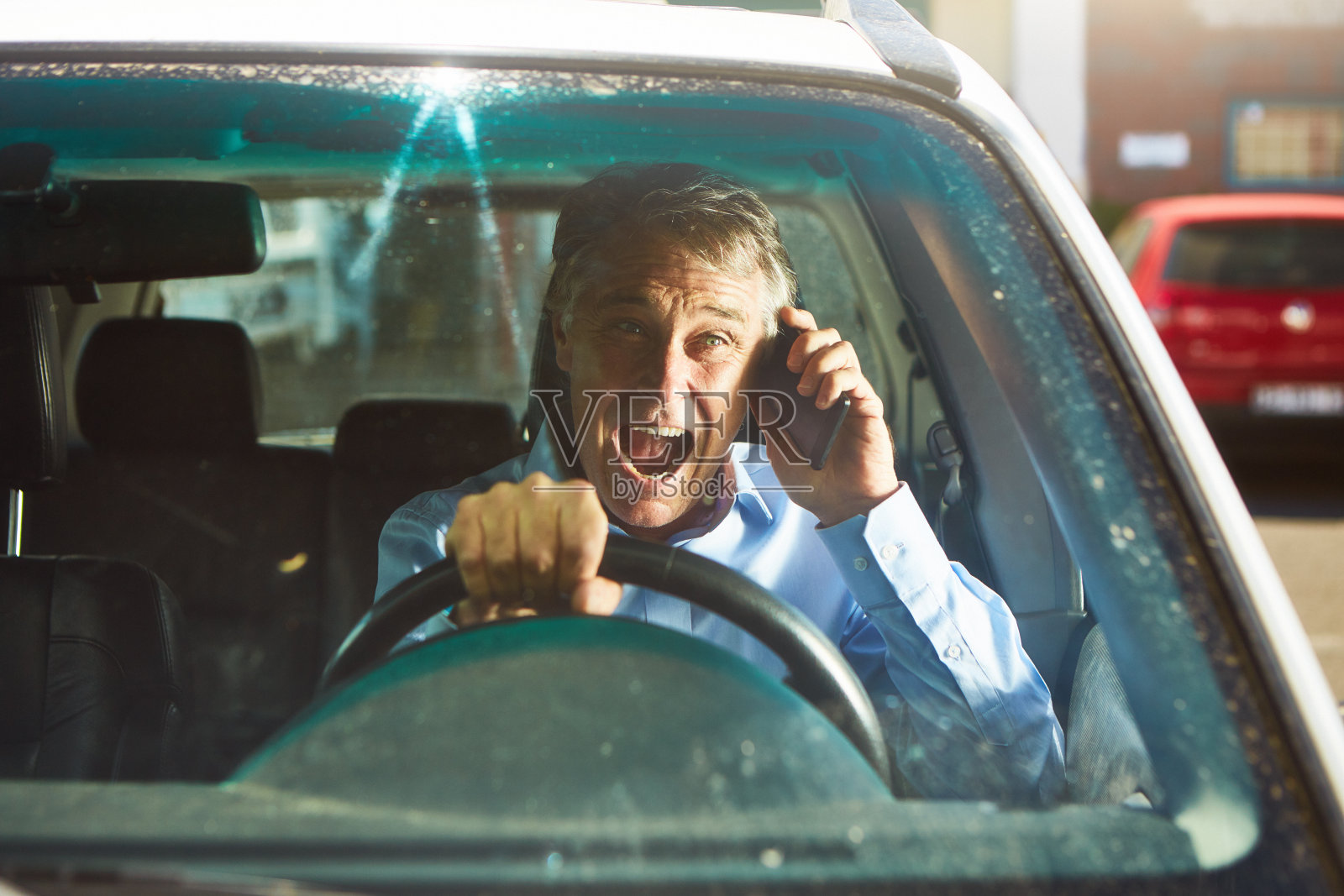 好消息:快乐的中年男子在车里用手机，看起来充满了快乐和幸福照片摄影图片