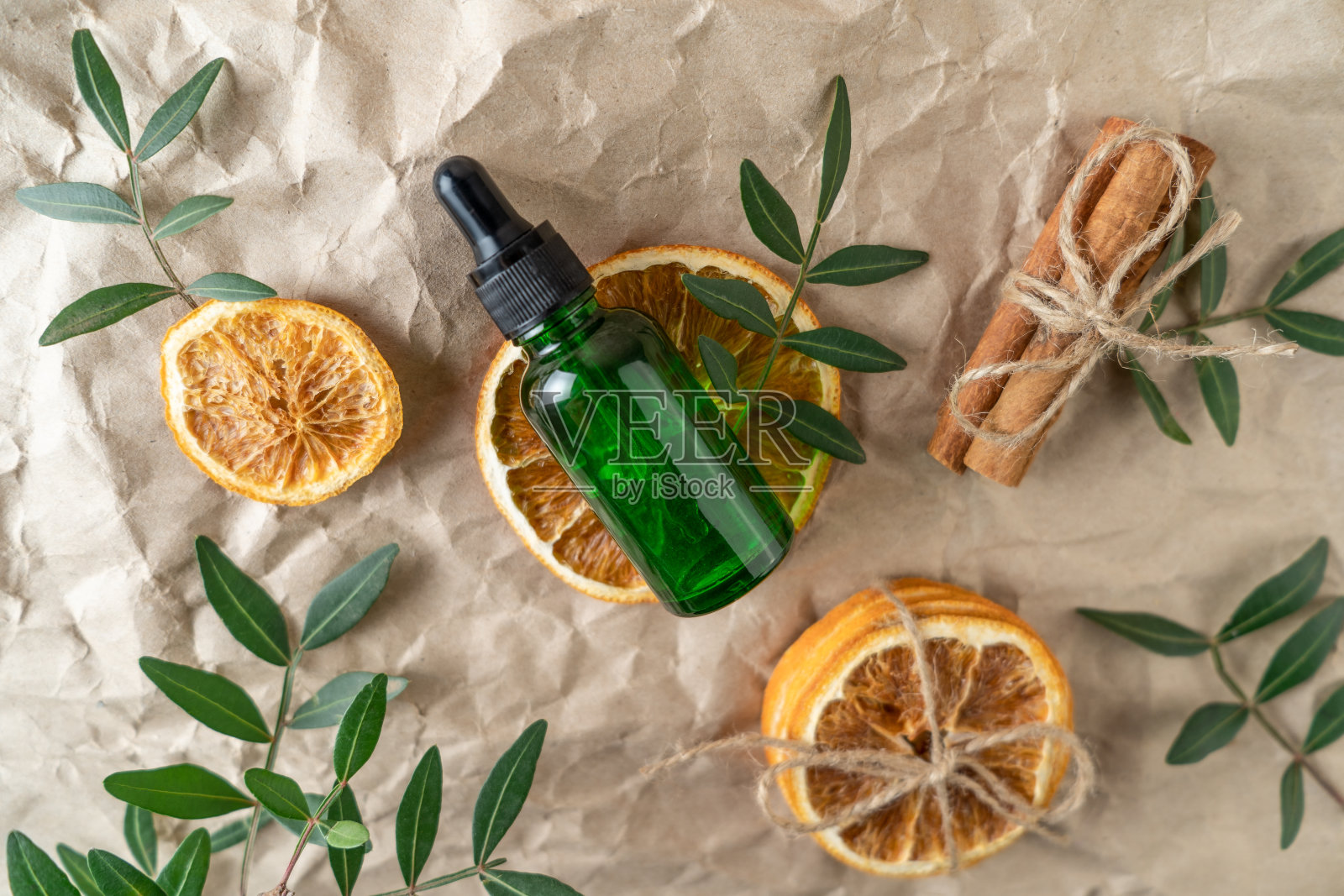 在米色的牛皮纸背景上，放着一个绿色滴瓶，里面装着面部精华液或精油照片摄影图片