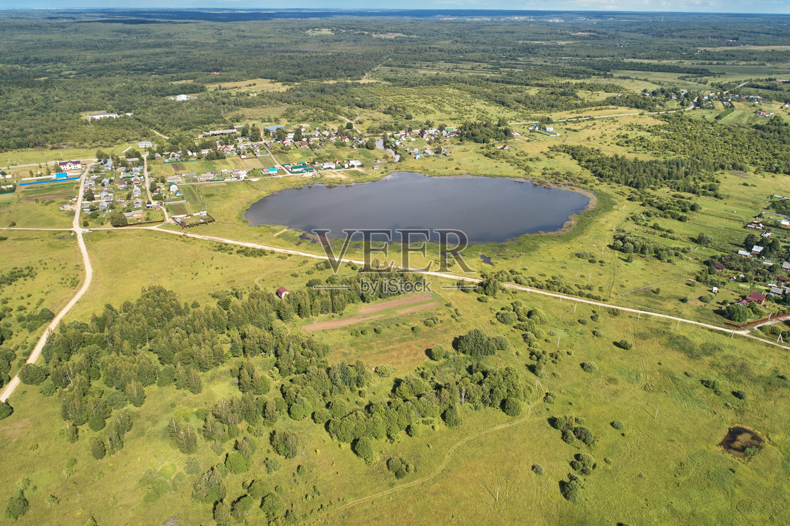 无人机航拍。有绿色森林、公路和湖泊的村庄。照片摄影图片