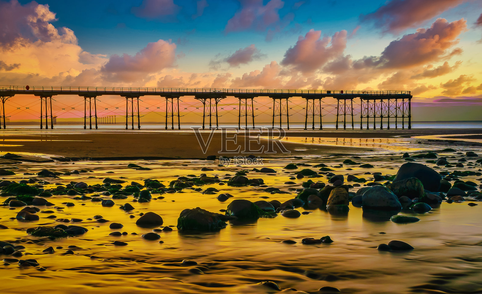 索尔本海岸的日落码头，前景是岩石照片摄影图片