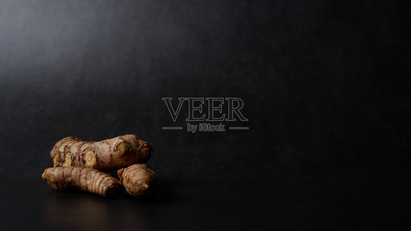 黑色背景下的姜黄根照片摄影图片