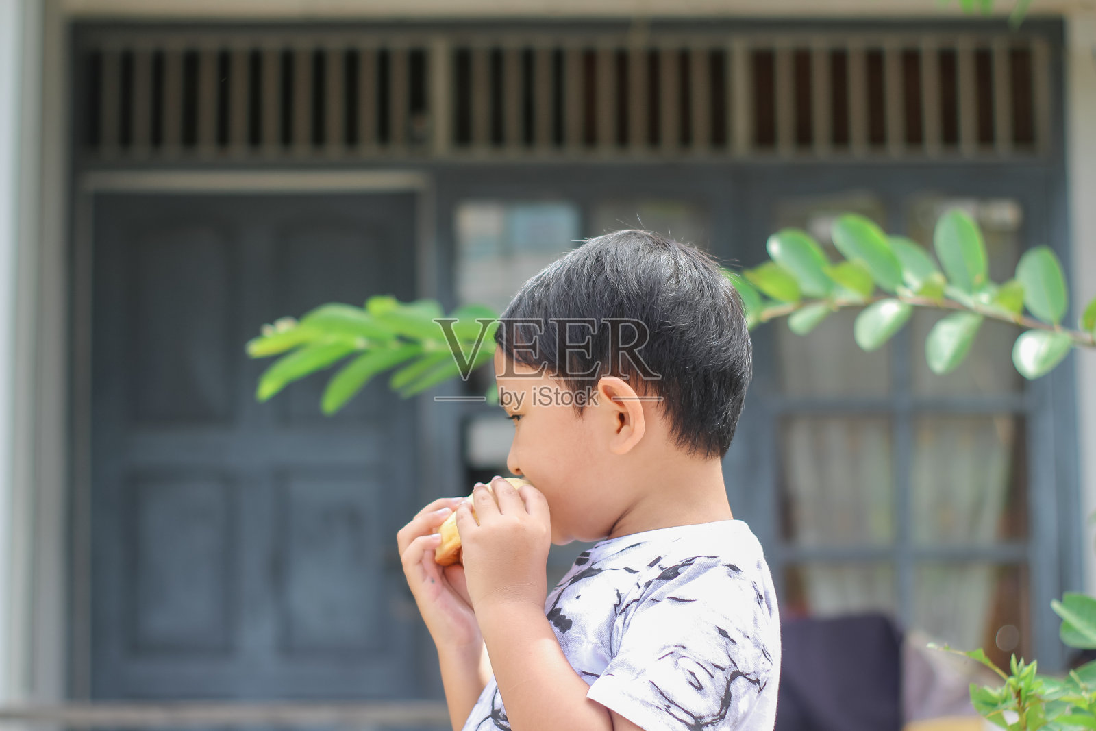男孩站在前屋吃面包照片摄影图片