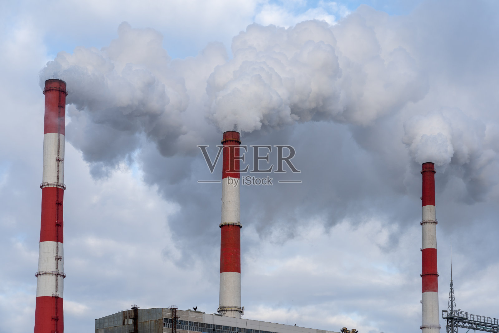 在蓝天的衬托下，从三个白红色的烟囱里冒出来的烟。照片摄影图片