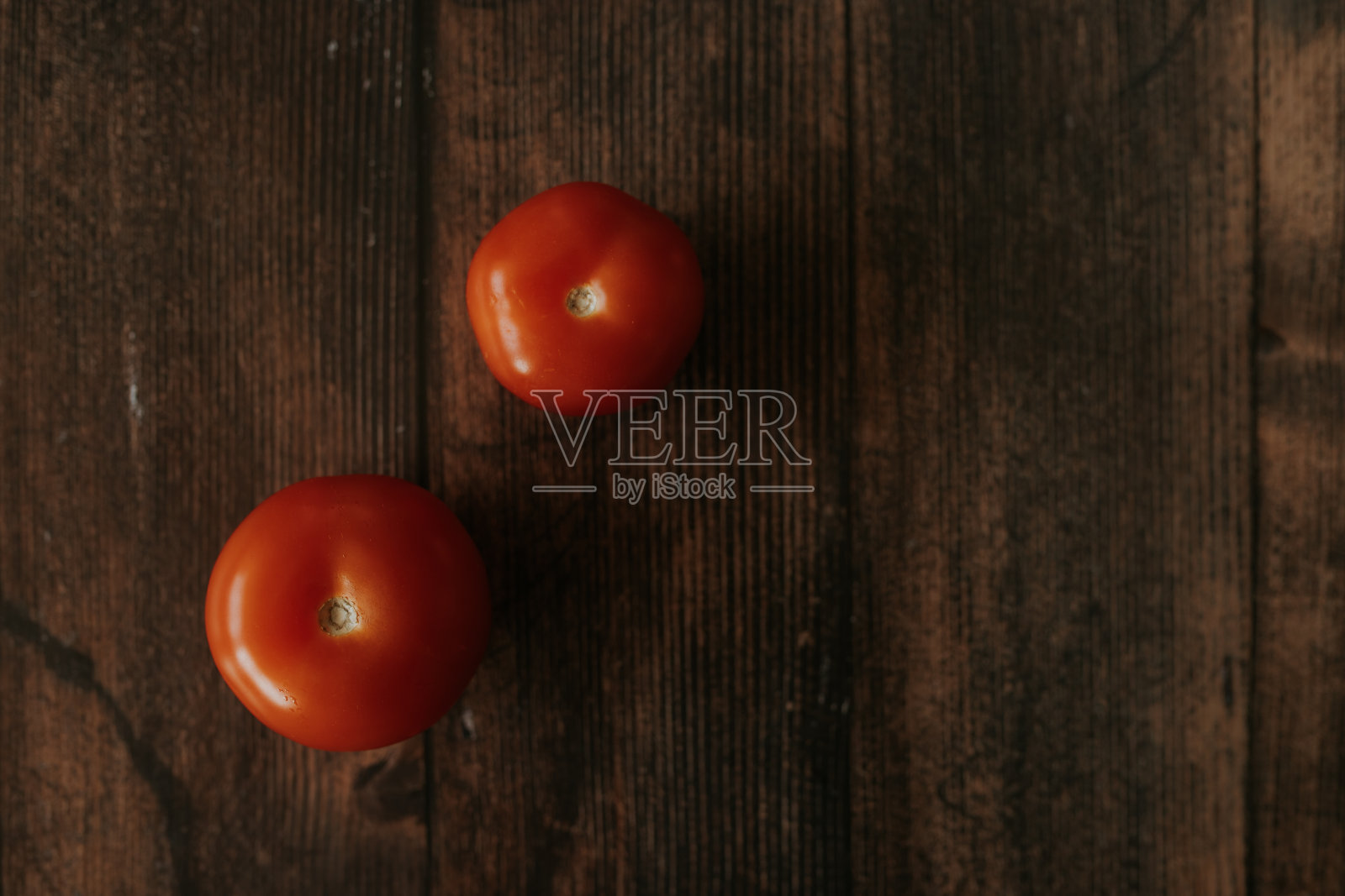 两个成熟的红色西红柿躺在一张木制的照片上。照片摄影图片