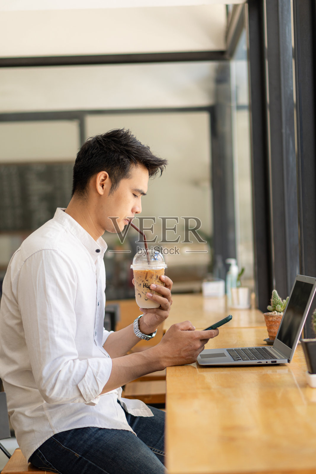 年轻的亚洲男性，未来的学生为自己或个人的学习想法。在线学生带着书和笔记本电脑在咖啡店里。照片摄影图片