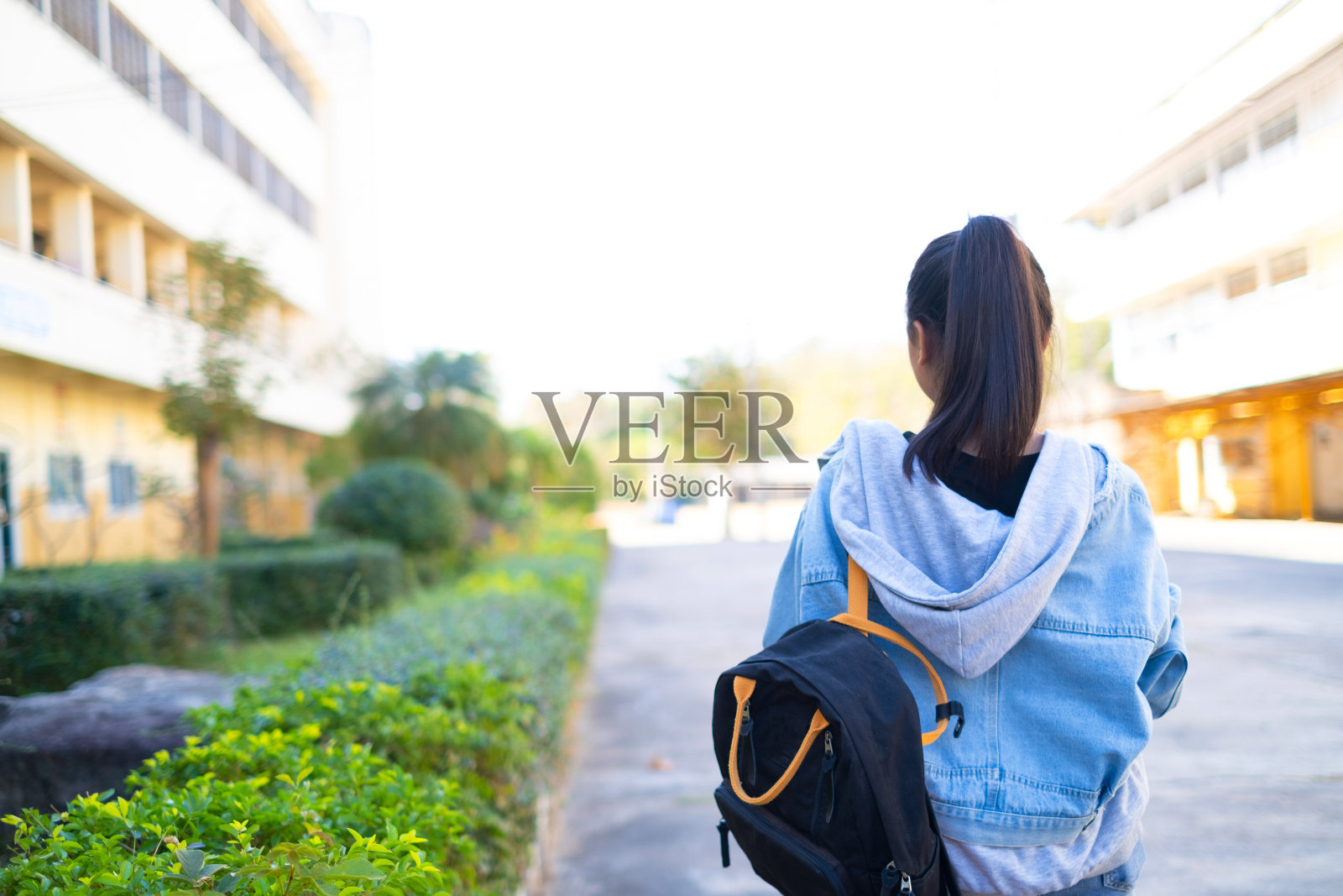 快乐的学生女孩拿着书和书包在学校，亚洲女孩。照片摄影图片