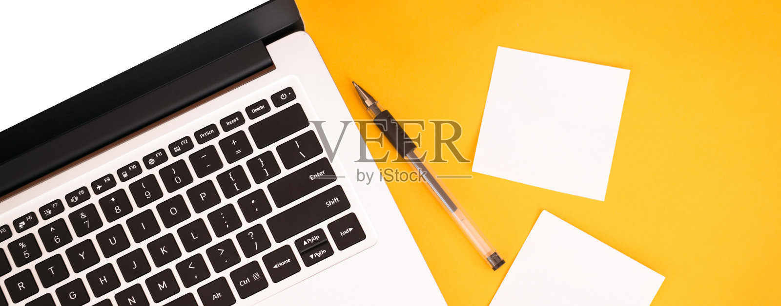 黄色背景的笔记本电脑横幅，贴纸和笔。文本。从以上观点。业务和远程工作的概念照片摄影图片