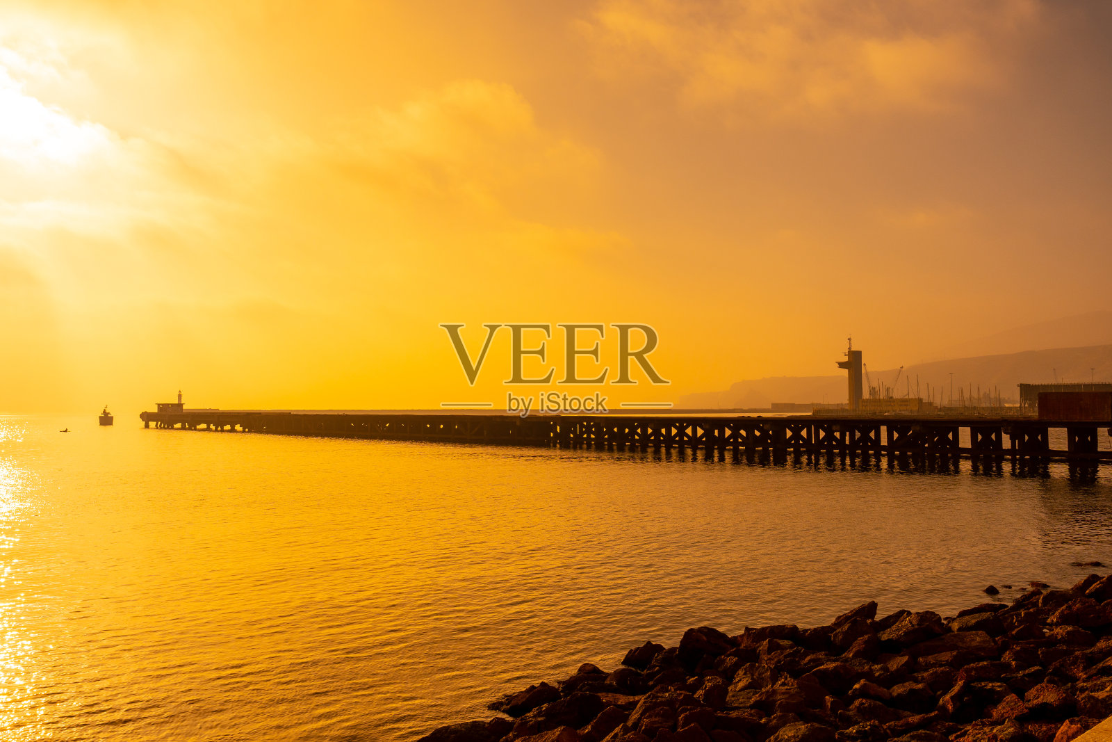 橙色日落时分，安达卢西亚阿尔梅里亚市圣米格尔海滩上一个名为“弗朗西斯电缆”的旧装货码头。西班牙。地中海的太阳海岸照片摄影图片