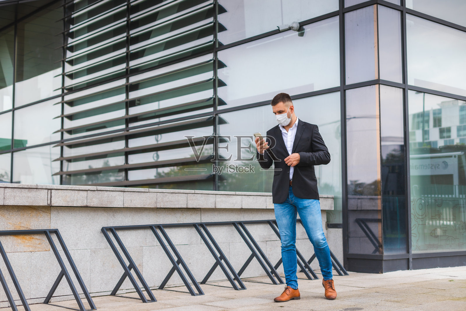 因新冠肺炎(COVID-19)感染，身穿黑色西装、戴着口罩的年轻商人正在打电话照片摄影图片