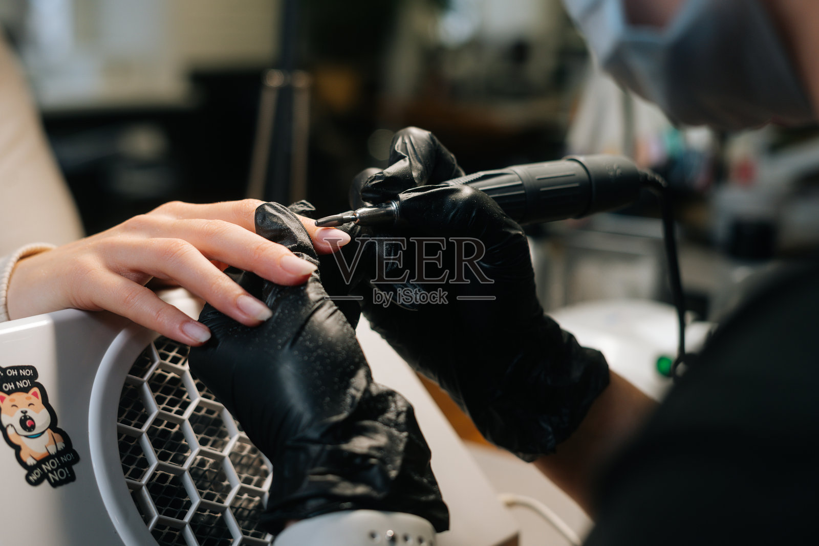 特写镜头，无法辨认的女美甲师去除凝胶polish或丙烯酸从指甲与美甲机的帮助。照片摄影图片