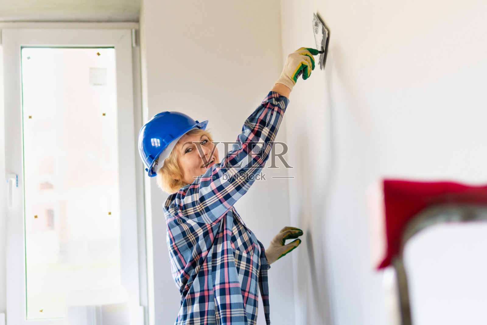 女建筑工人在房子的房间里修理。照片摄影图片