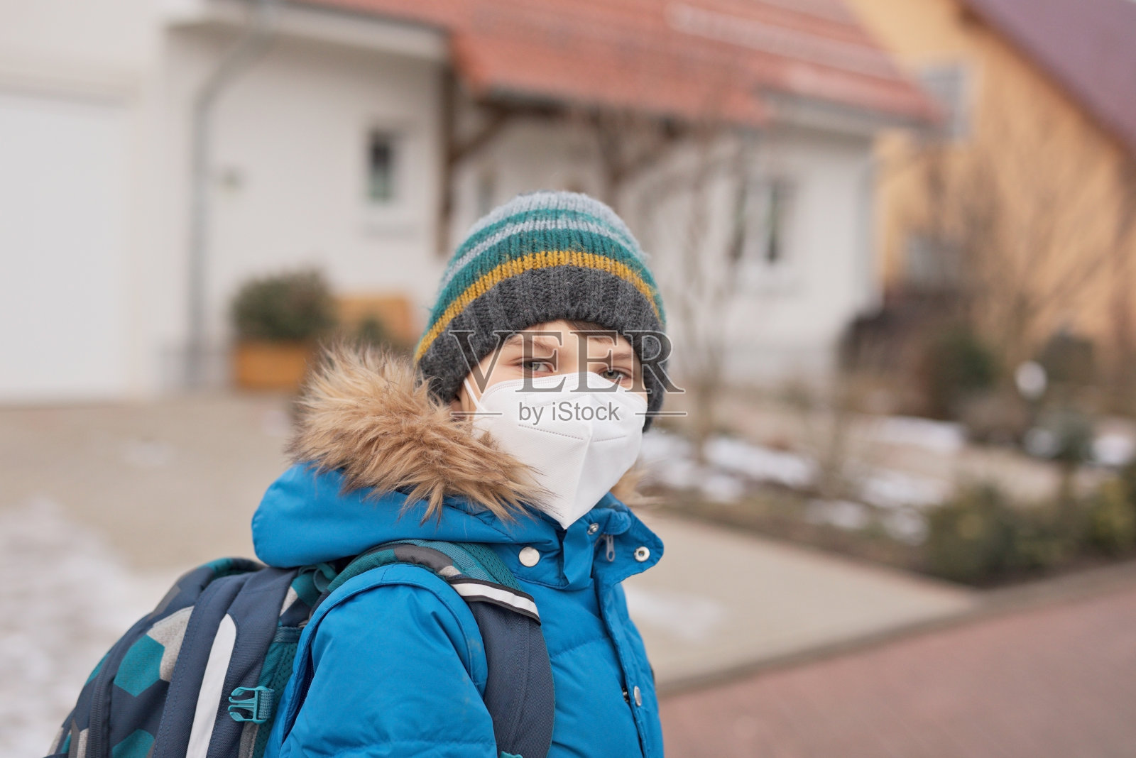 一个戴着医用口罩上学的男孩。孩子背包背包。学生在寒冷的秋冬日子穿着暖和的衣服。冠状病毒大流行期间的封锁和隔离时间照片摄影图片
