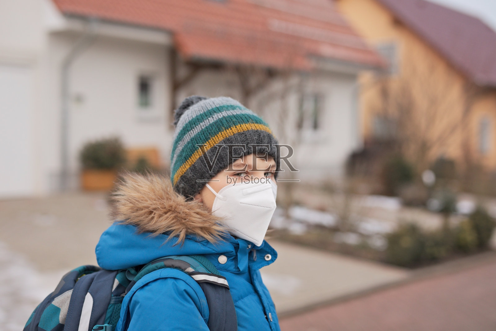 一个戴着医用口罩上学的男孩。孩子背包背包。学生在寒冷的秋冬日子穿着暖和的衣服。冠状病毒大流行期间的封锁和隔离时间照片摄影图片