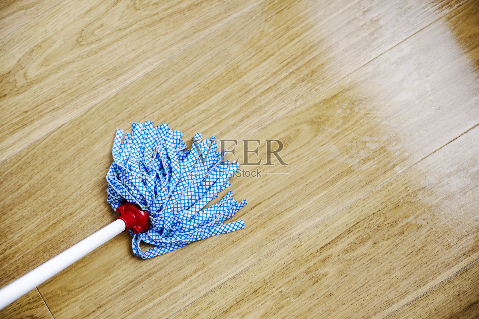 在家里用拖把清洁镶木地板。照片摄影图片