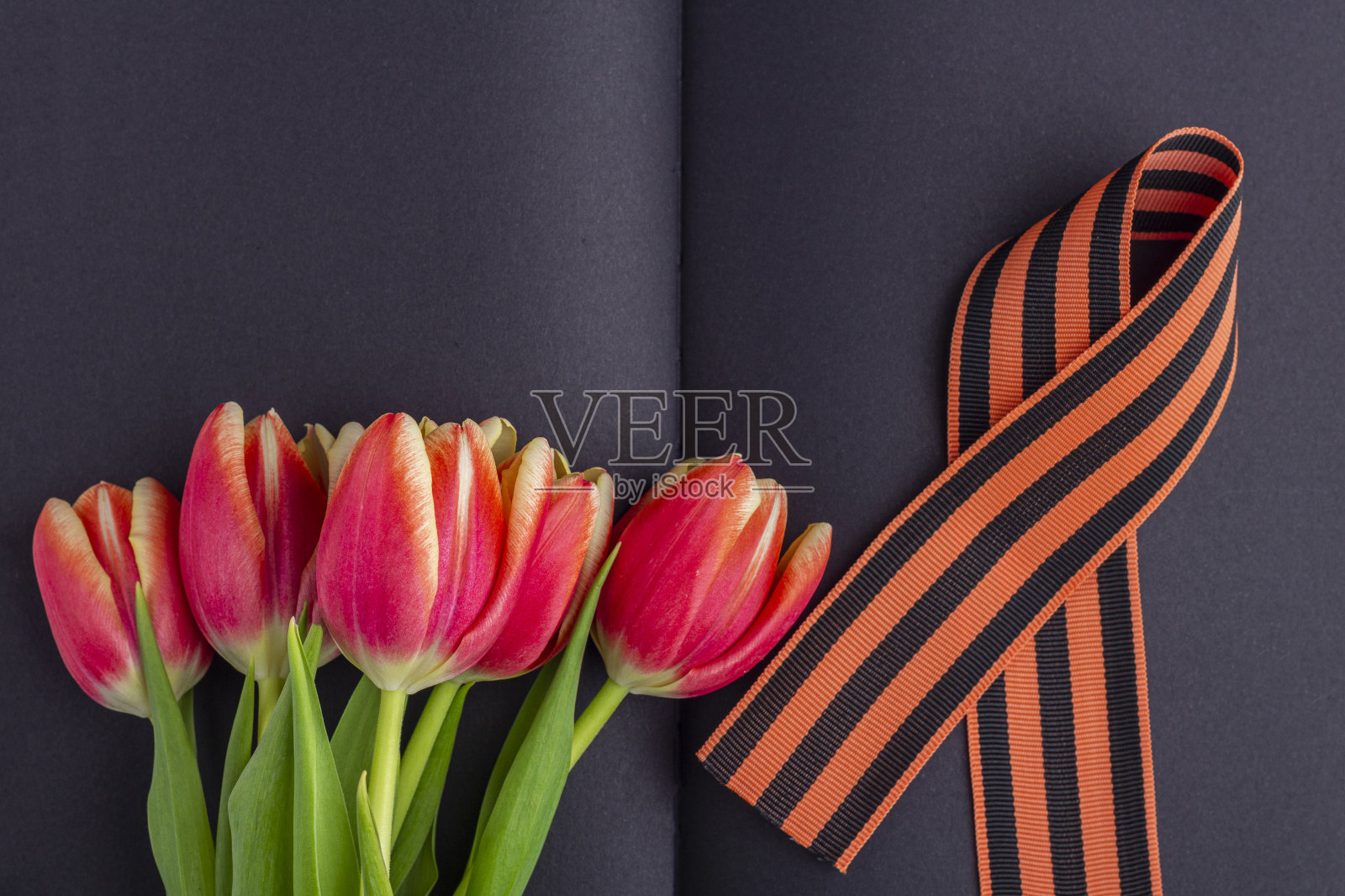 模板空白贺卡到5月9日。红花(郁金香)，黑色笔记本上的乔治丝带。胜利日或祖国卫国日的概念。俯视图，文本的拷贝空间照片摄影图片