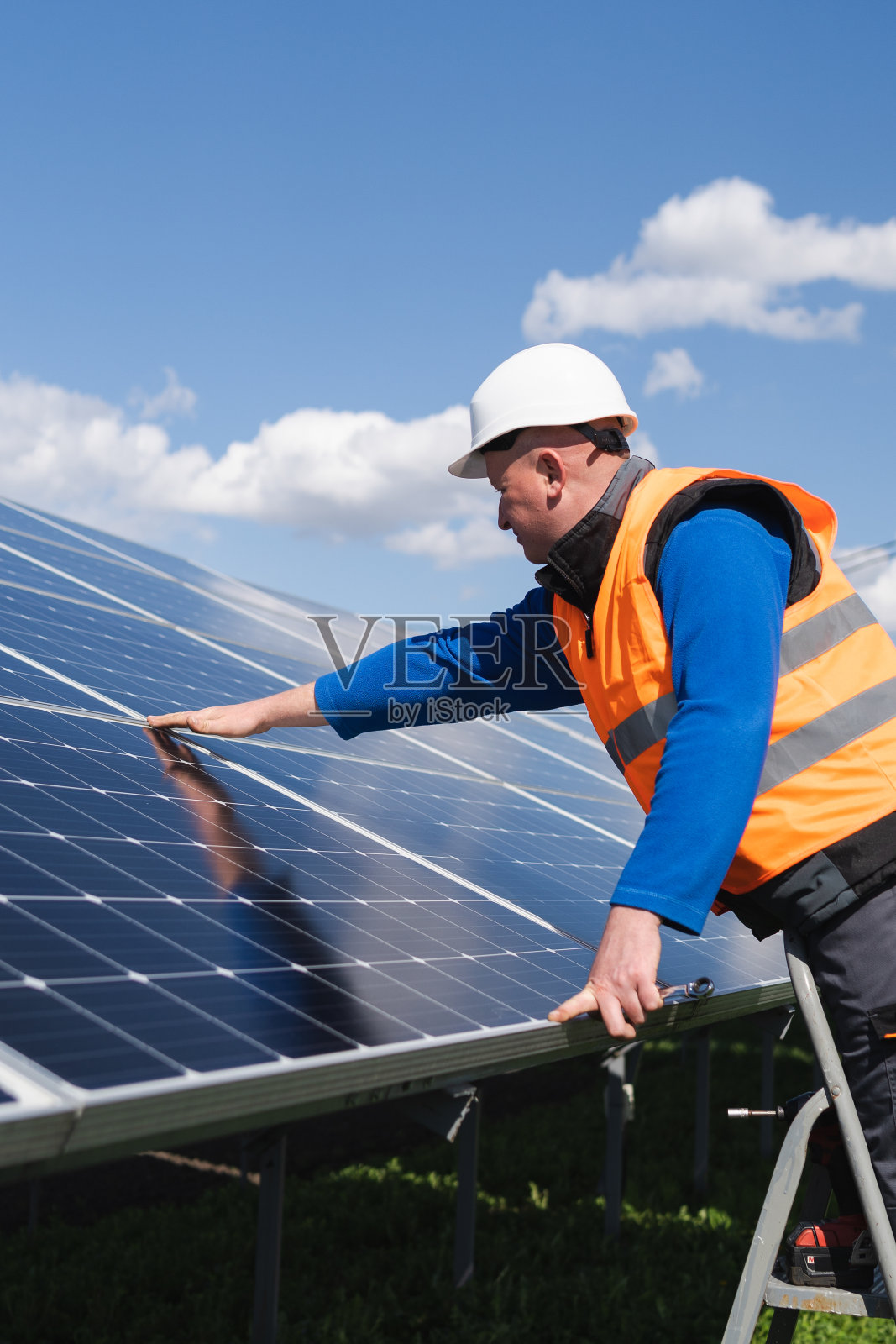 太阳能发电厂工人在梯子上对太阳能电池板进行目视检查照片摄影图片
