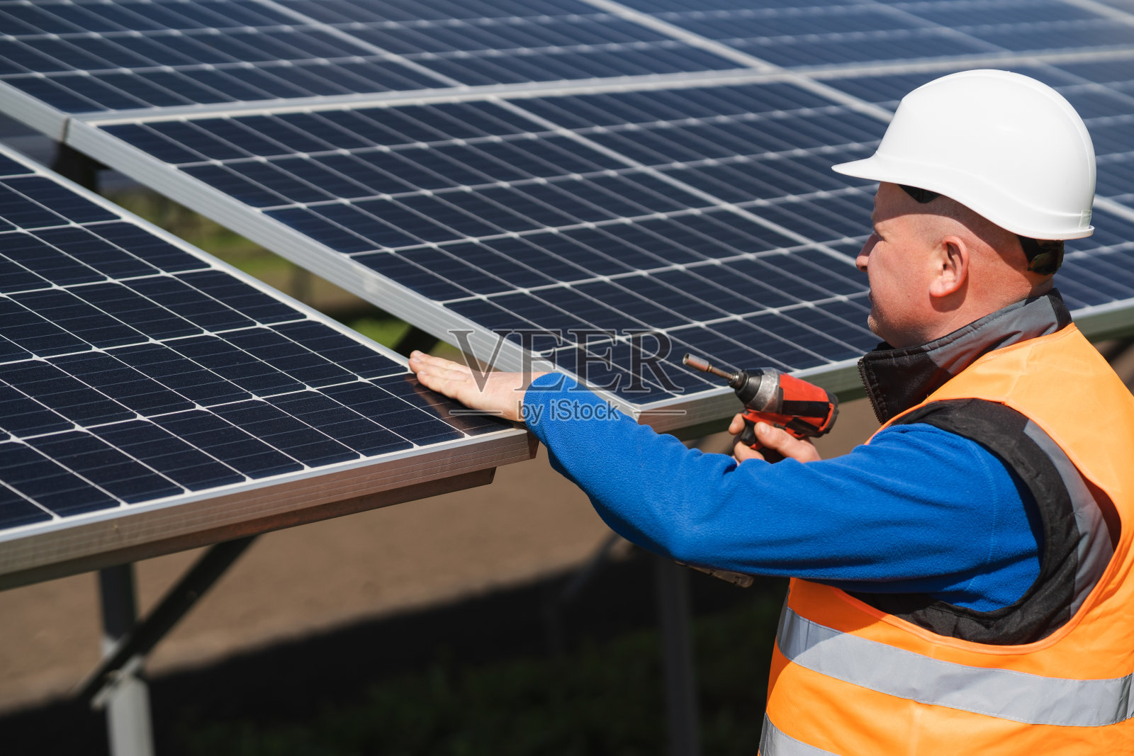 太阳能发电厂的工人手里拿着电动扳手在检查面板照片摄影图片