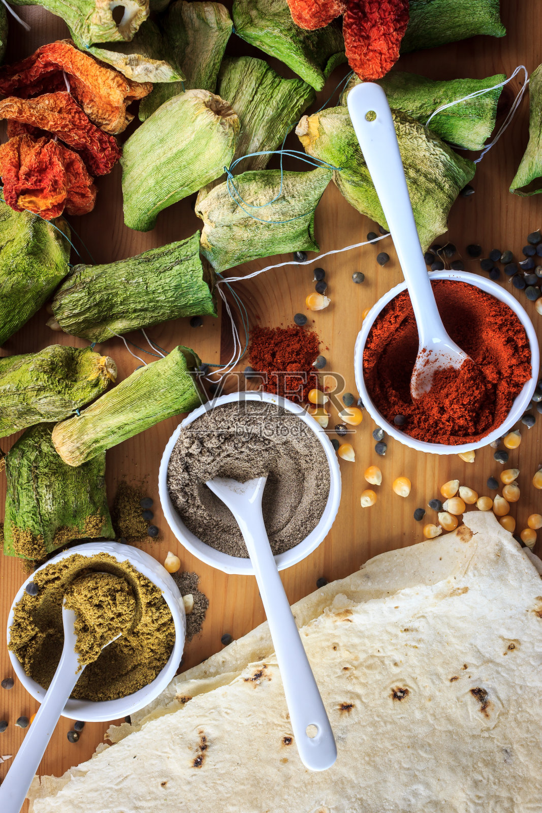 从俯视图可以看到干辣椒和西葫芦，碗里放着香料，木桌上放着玉米和尤夫卡面包照片摄影图片