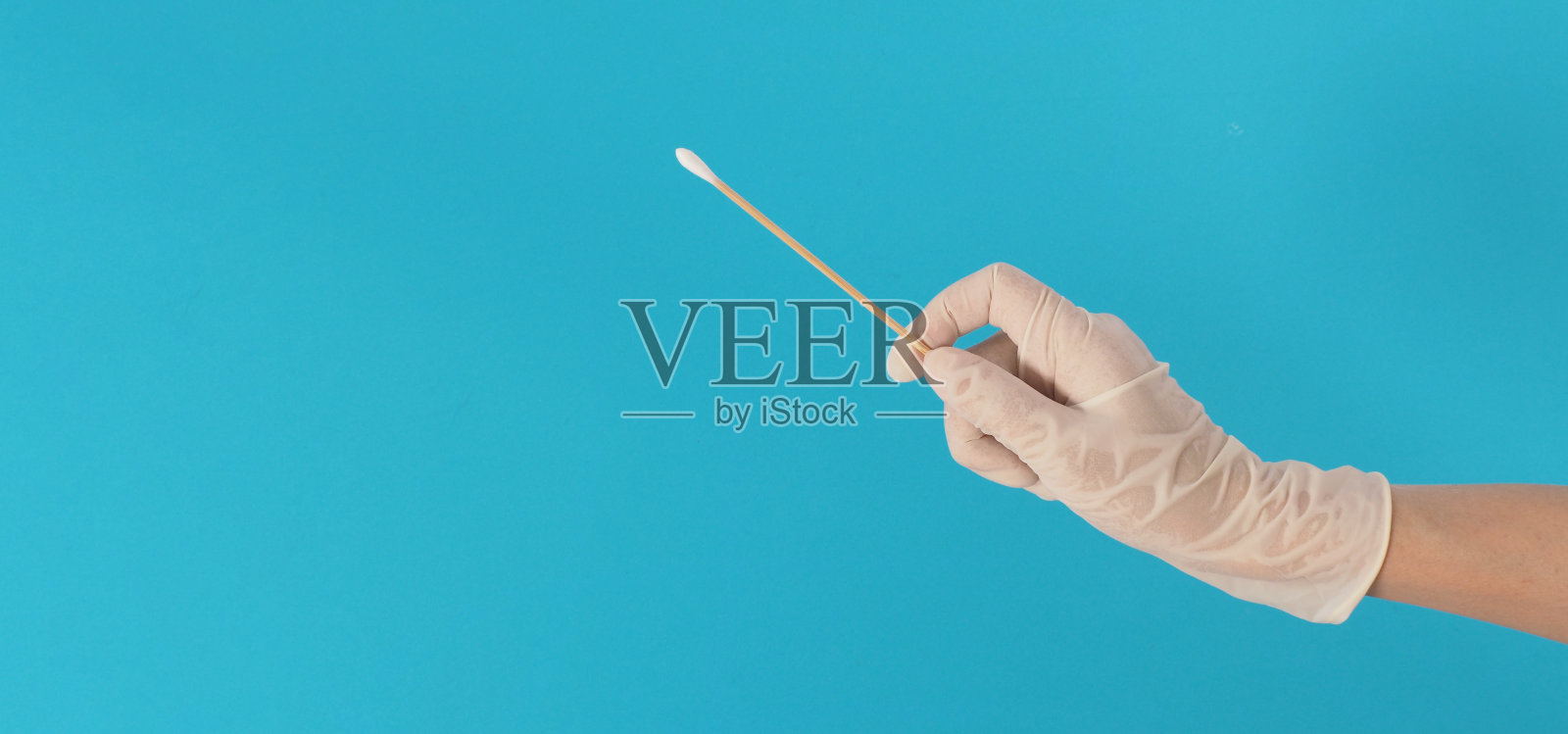 用棉签做拭子试验，用白色医用手套或蓝色背景的乳胶手套。照片摄影图片
