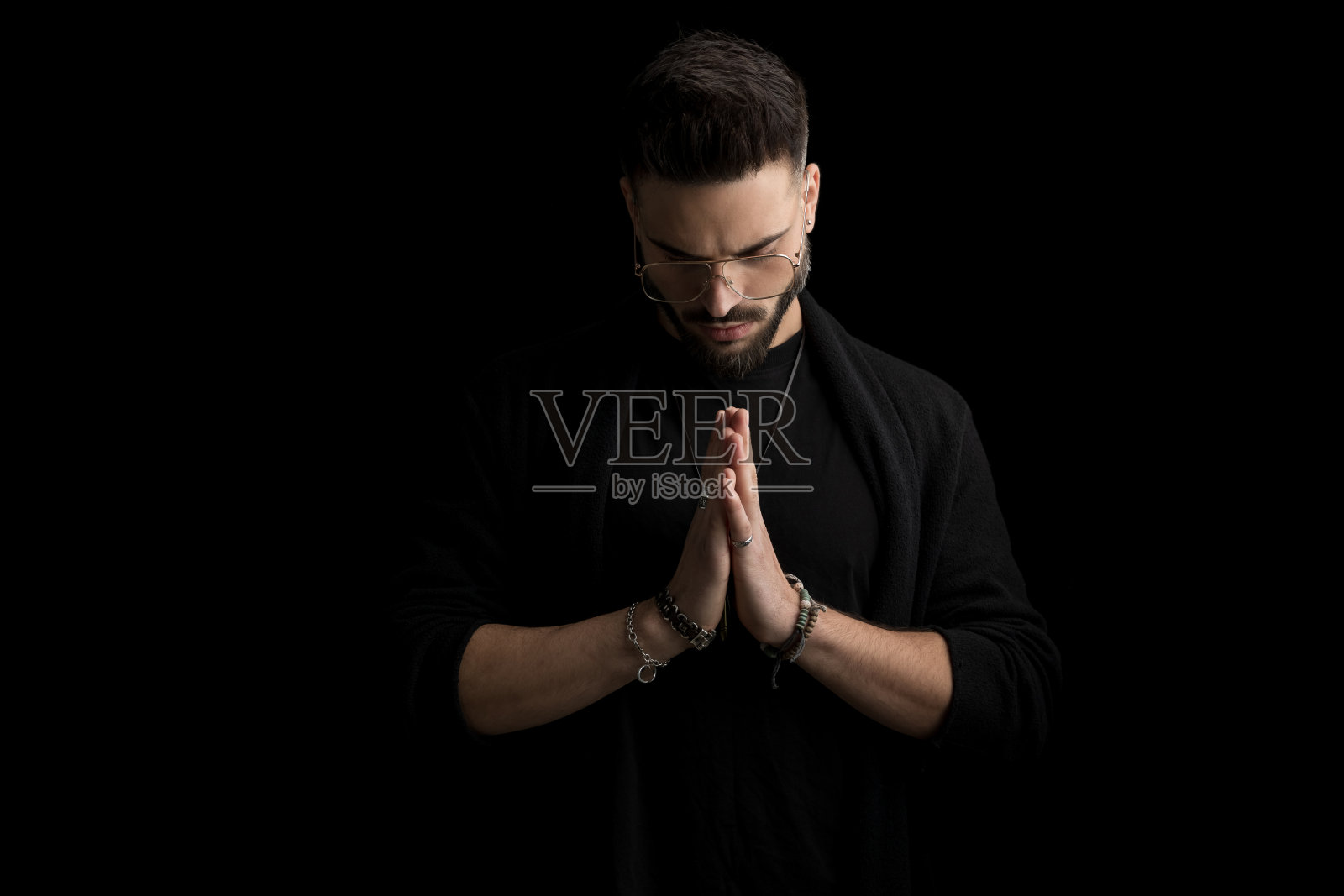 英俊的不刮胡子的年轻人，手牵眼镜照片摄影图片