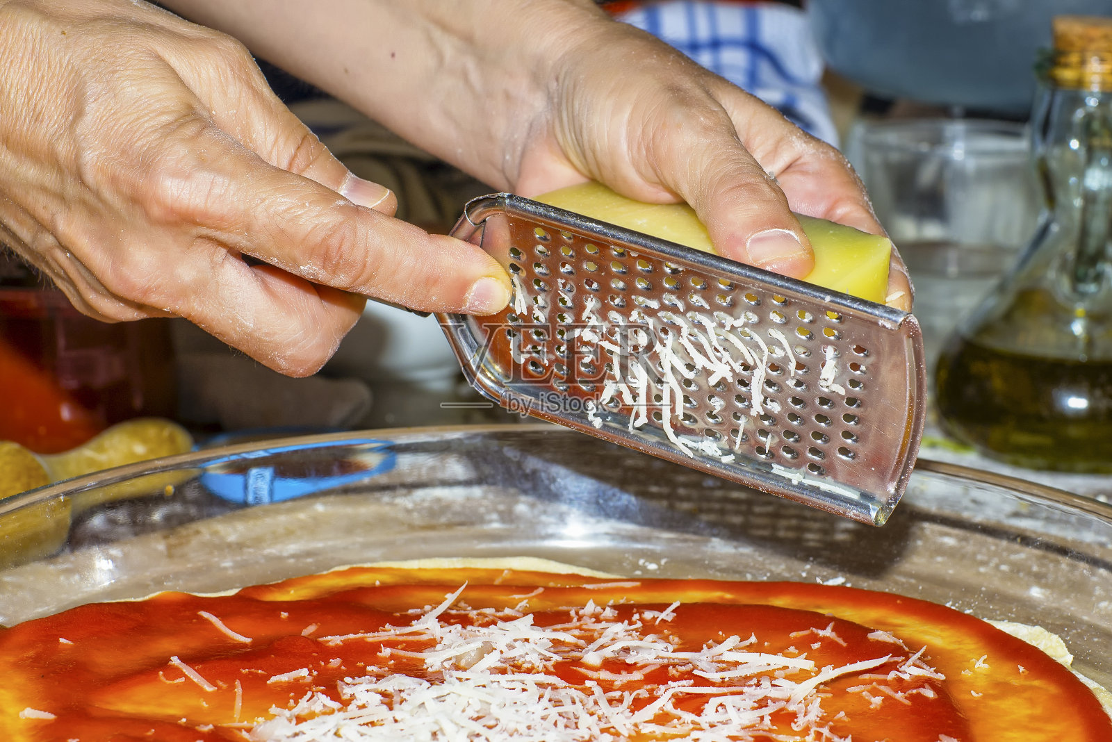 用磨碎器磨碎披萨中的奶酪照片摄影图片