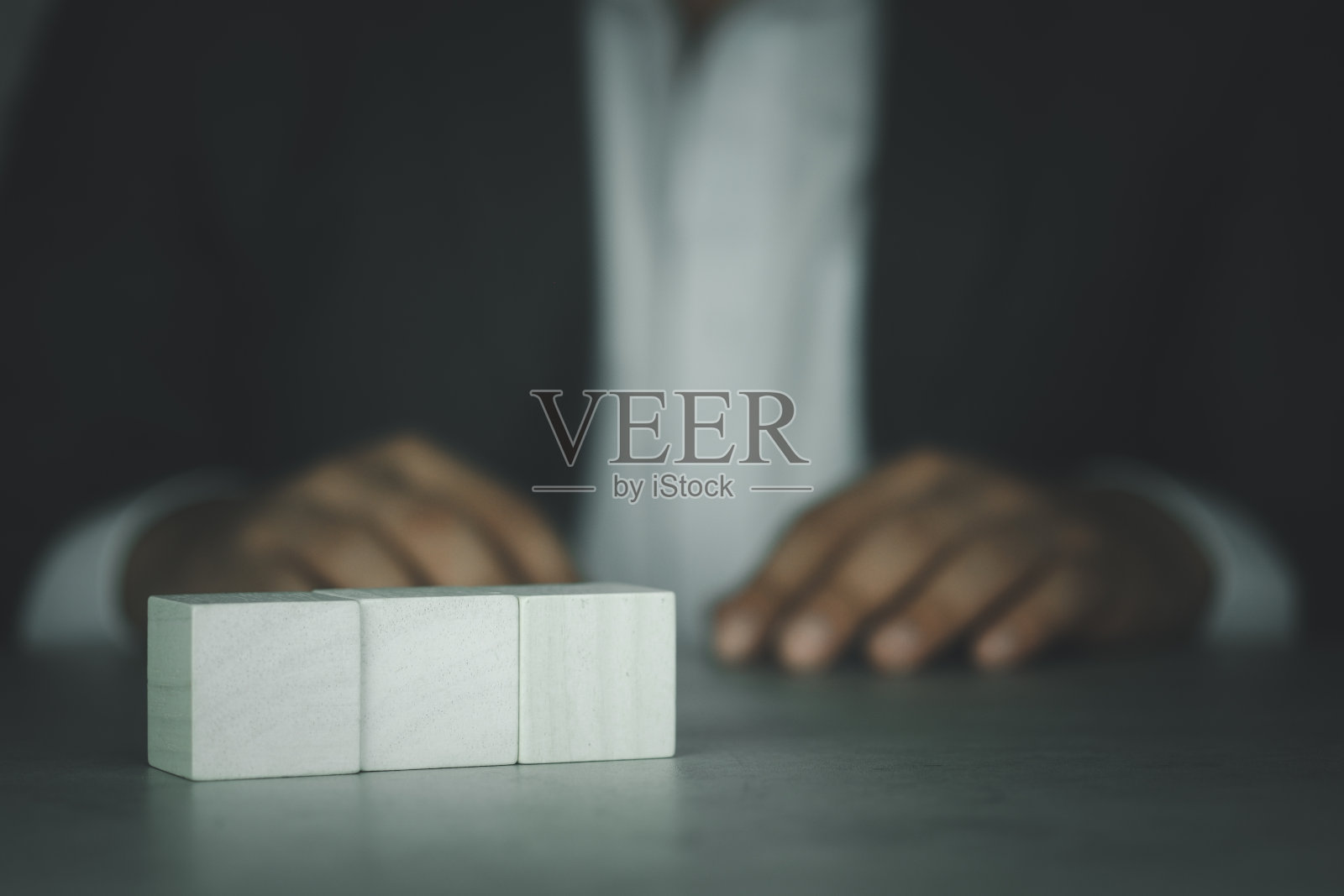 空木块立方体在桌子的背景与西装商人。照片摄影图片