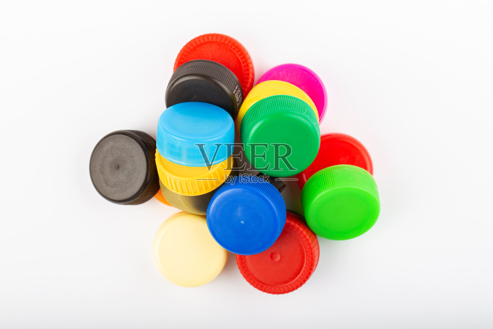白色背景上的彩色塑料帽堆。回收的概念。照片摄影图片