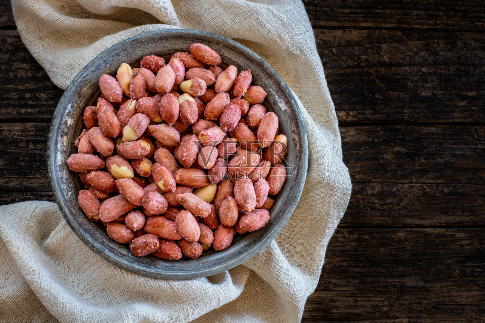 许多花生在古老而质朴的木碗上。照片摄影图片
