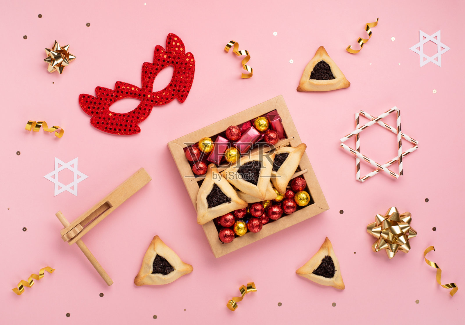 节日美味的哈曼塔森饼干，红色的狂欢节面具，噪音制造者，糖果和派对装饰在粉红色的背景。照片摄影图片