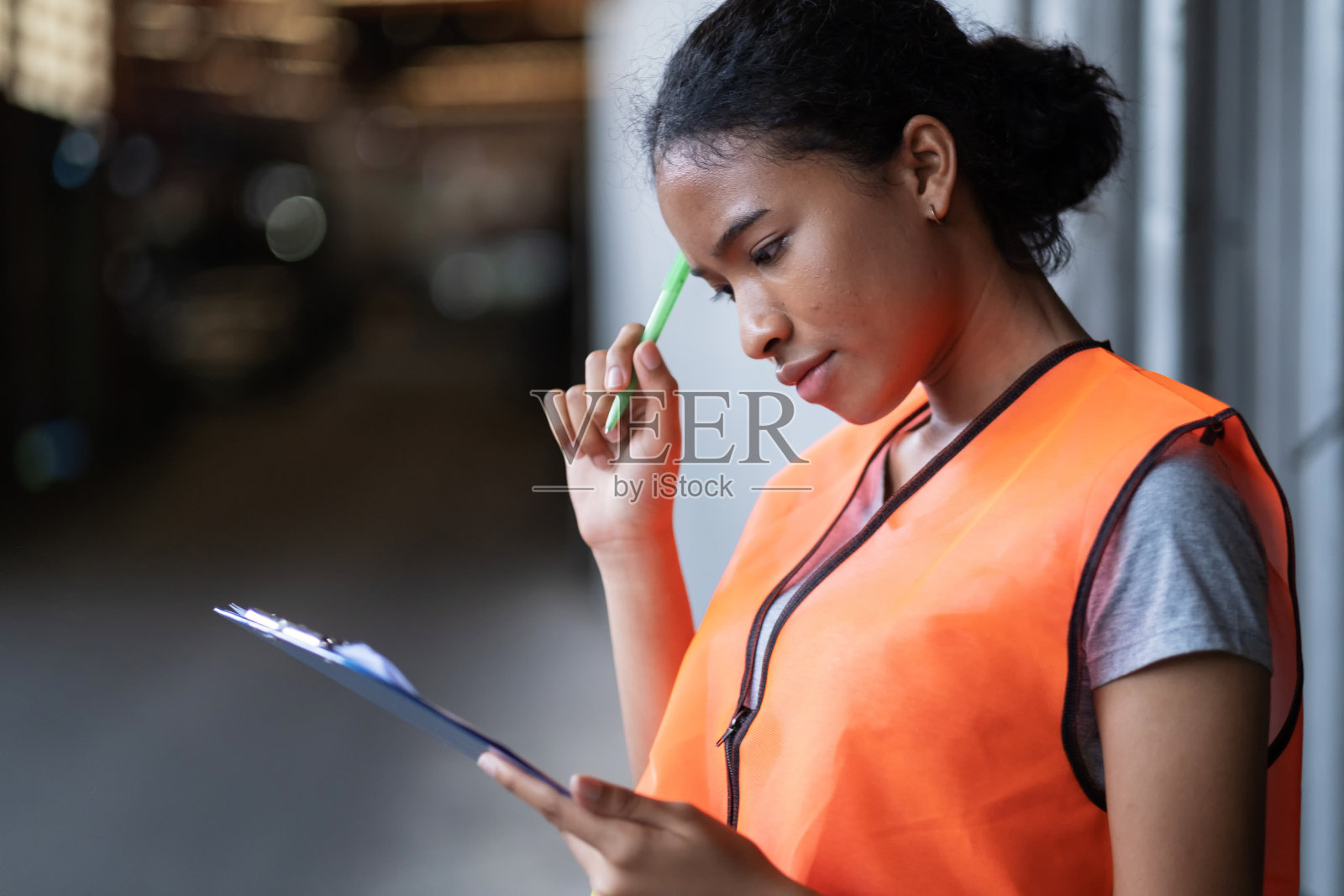 非裔美籍女工程师穿着背心站在工厂的汽车发动机零件。工人在车库里拿着剪贴板和检查清单。看笔记。产业与股票概念照片摄影图片