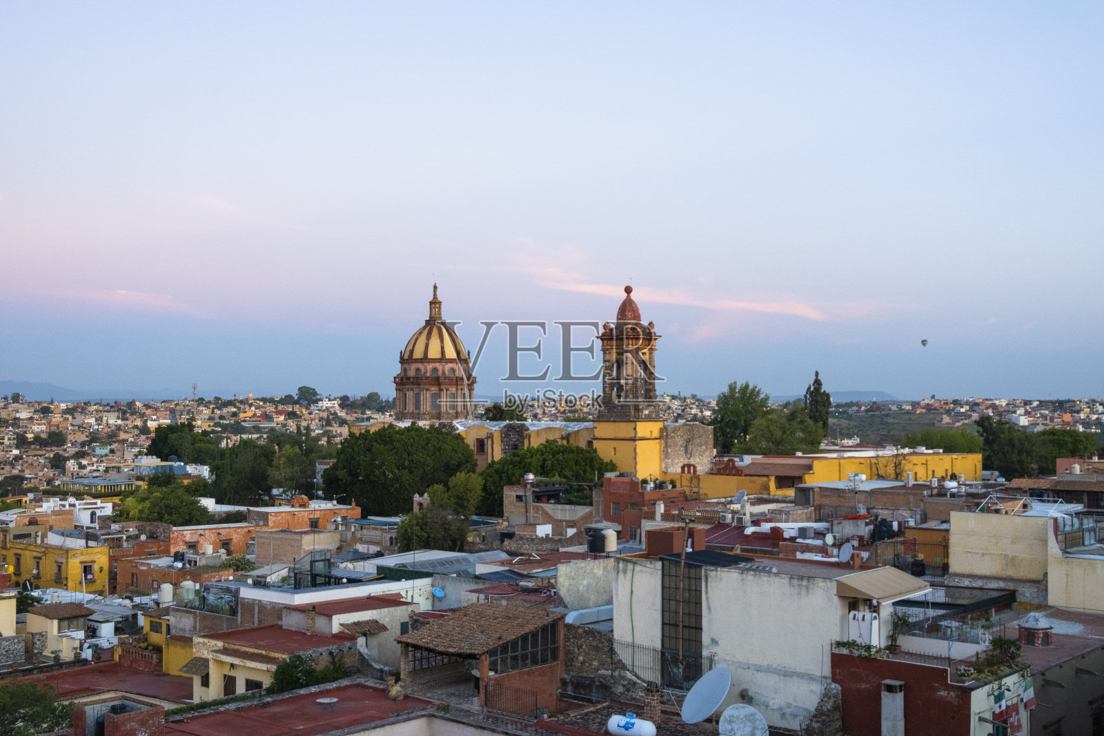墨西哥圣米格尔德阿连德，在日出时的背景中，房屋屋顶和圣灵感孕会的全景照片摄影图片