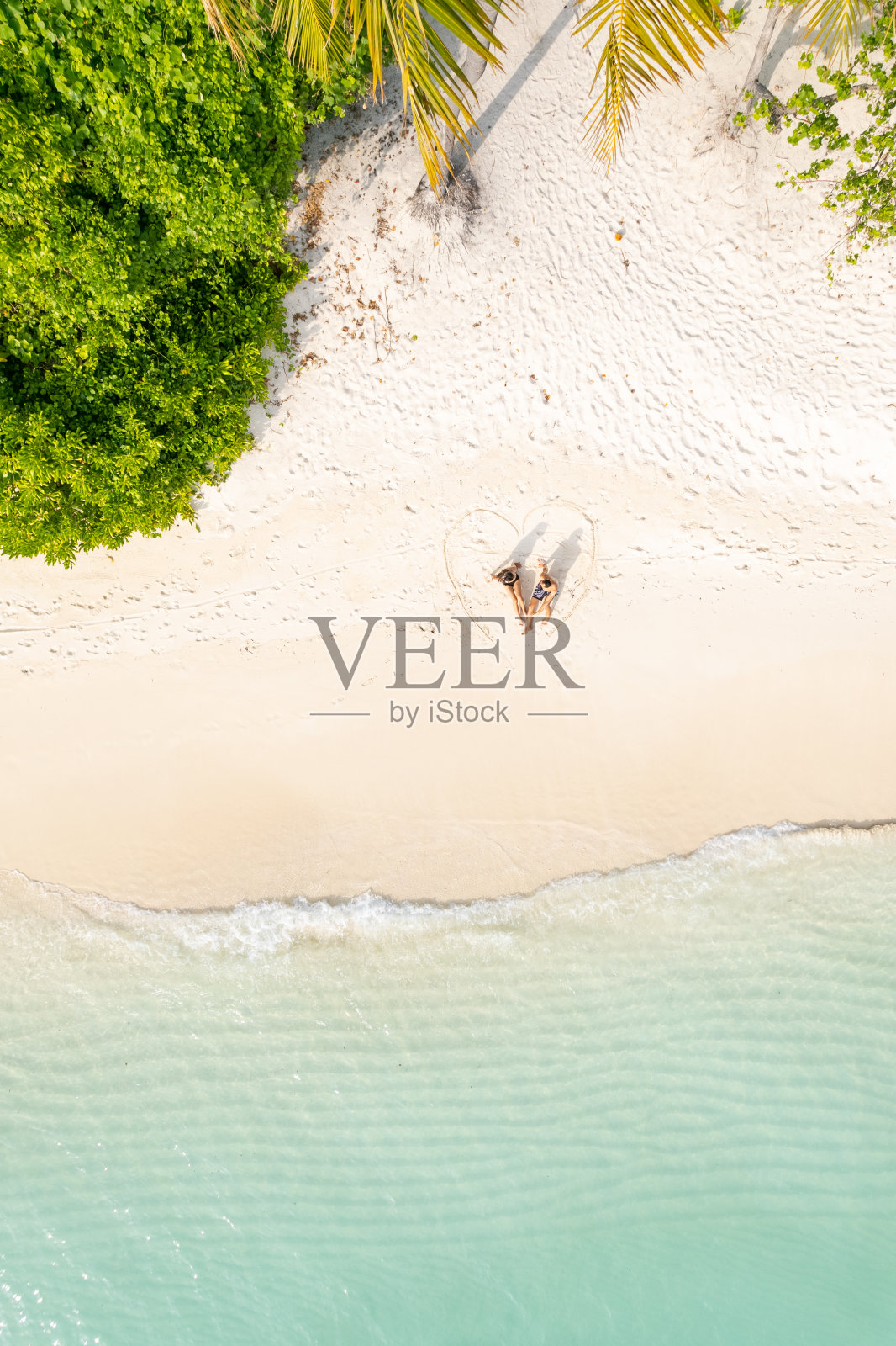 夫妇坐在心形画在海滩上照片摄影图片