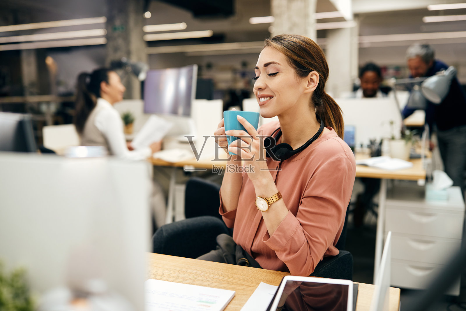 年轻的女商人在办公室休息时享受着新鲜咖啡的香味。照片摄影图片