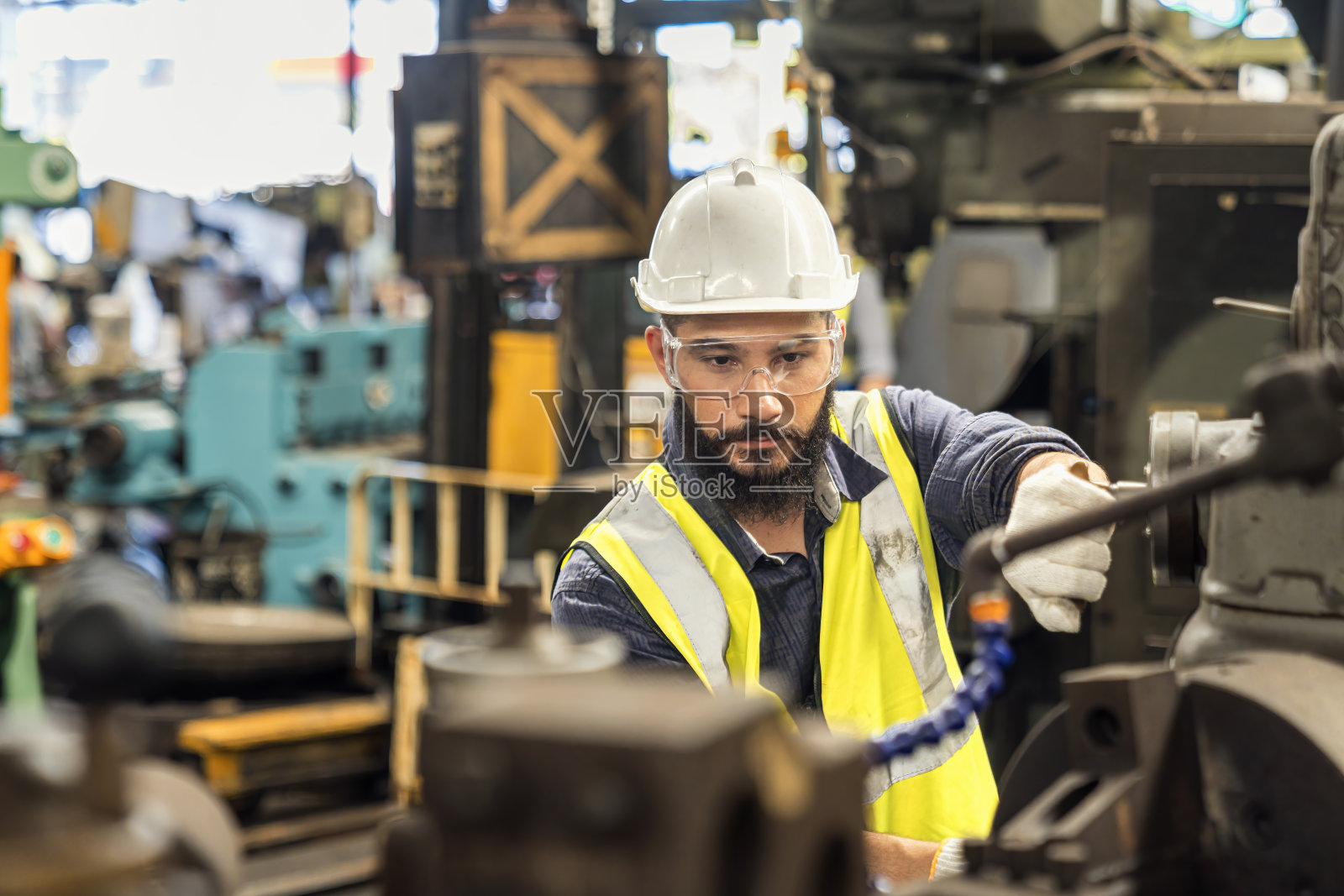 技工正在一家钢铁厂工作。戴安全帽的工人在钢铁机器上工作。照片摄影图片