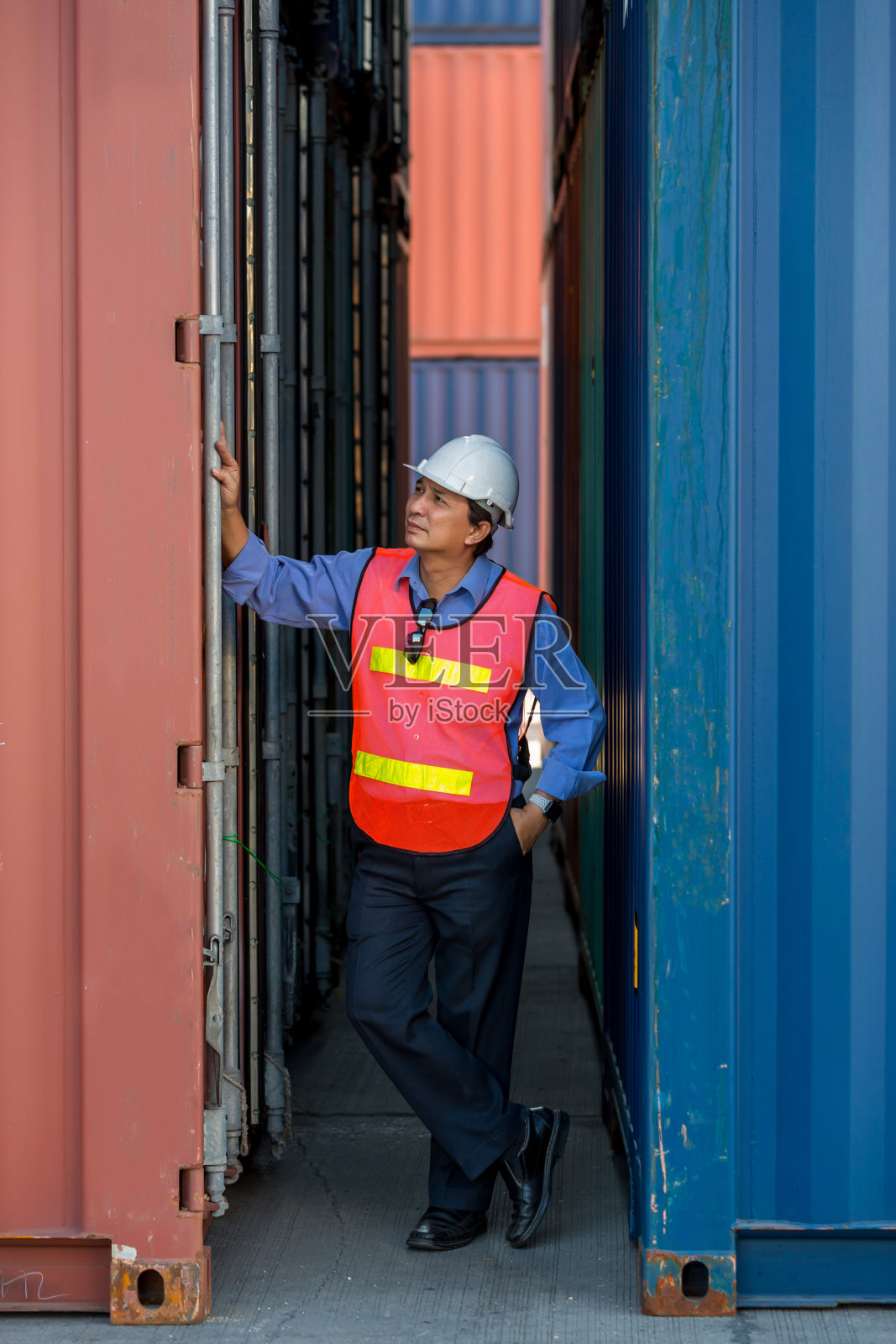 专业的领班在集装箱货场工作，检查集装箱内的货物。工人们正在打开集装箱接受检查。照片摄影图片