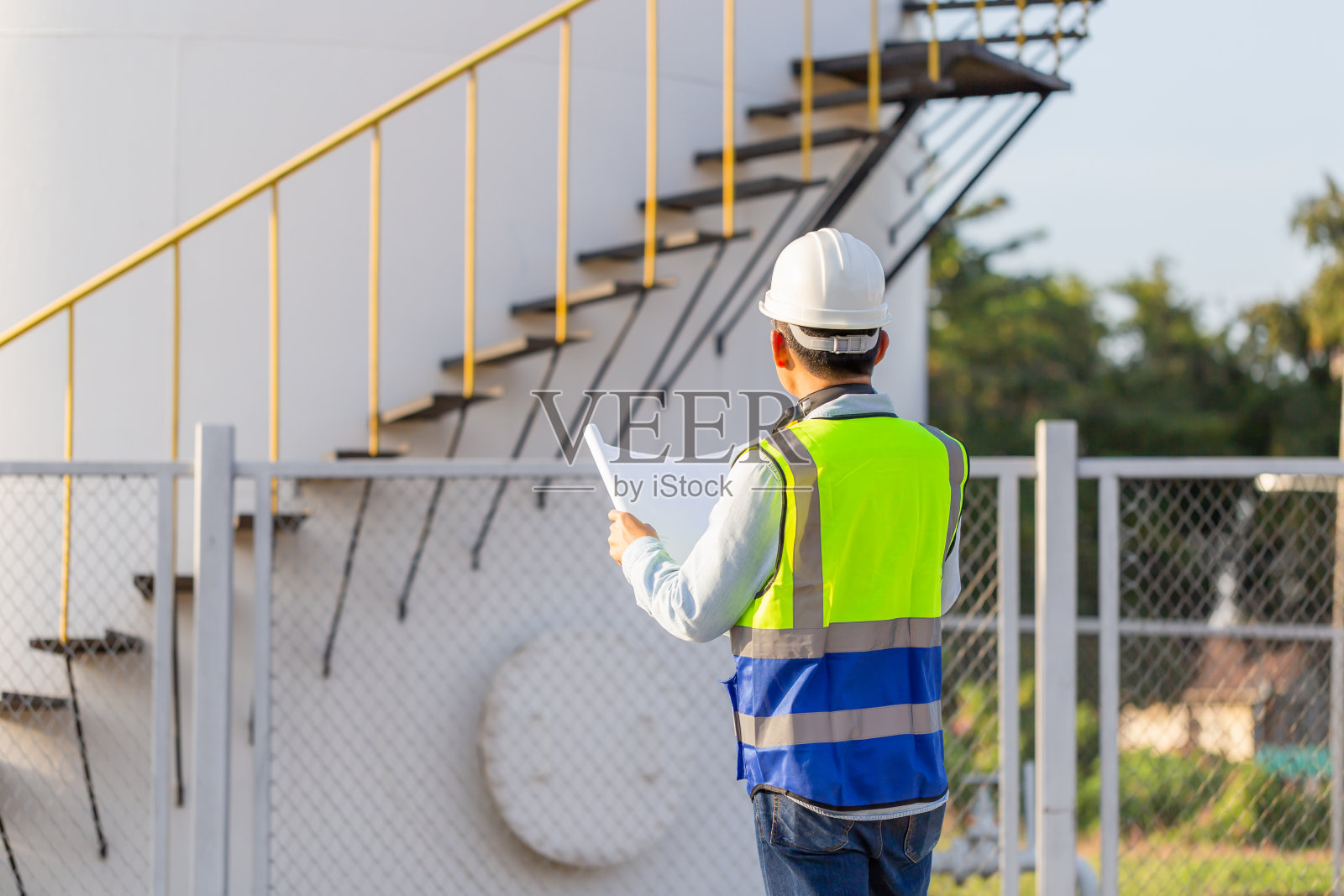 工程师在检查和检查油罐，工程师在油库工厂穿着马甲和安全帽并携带文件照片摄影图片